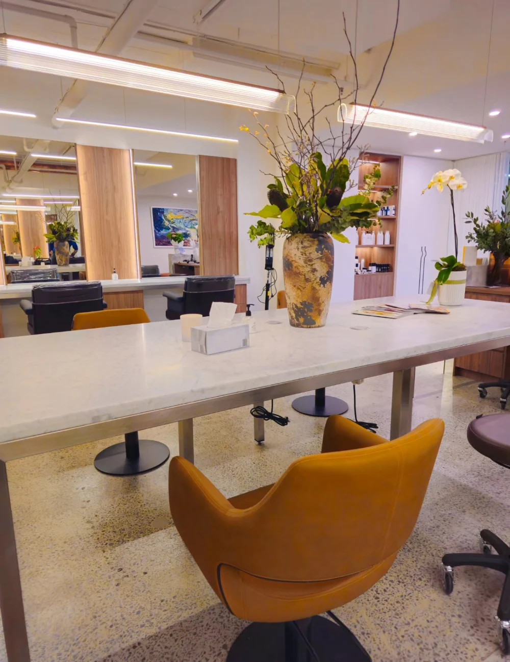 The styling floor at Hair By Konstantinos in Toorak, with the marble bench, mirrors and tan leather chairs